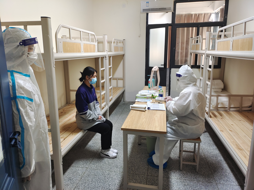 校医在隔离室对学生进行测温与记录